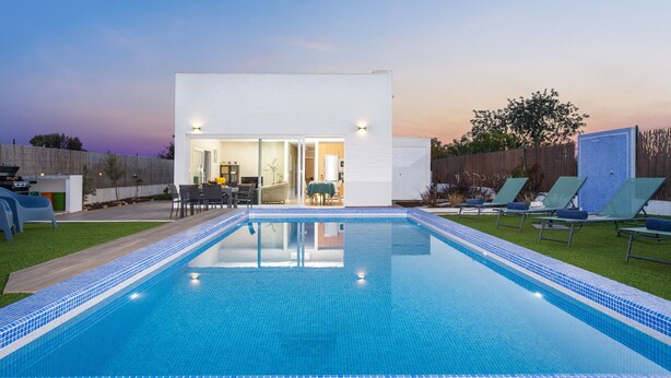A modern outdoor pool area with a clear blue pool, lounge chairs, and a patio with a table and chairs. - Peaceful villa w/ pool, BBQ & ping-pong table (Alcantarilha)
