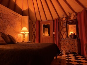 Una habitación con cama, lámpara, cómoda, espejo y un mapa en la pared.