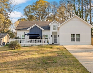 Ein Bungalow mit Garage, überdachter Veranda und umzäunter Garten.