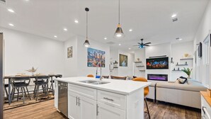 A modern kitchen with white cabinetry, a central island, and pendant lighting. - Atlanta Game House with Hot Tub (Riverdale)