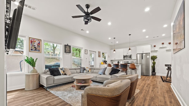 A modern living room with a sofa, armchairs, a coffee table, and a ceiling fan. - Atlanta Game House with Hot Tub (Riverdale)