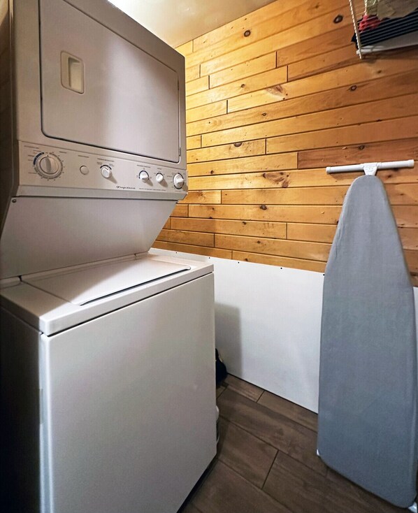A compact kitchen with a white stove, a drying rack, and wooden wall paneling.