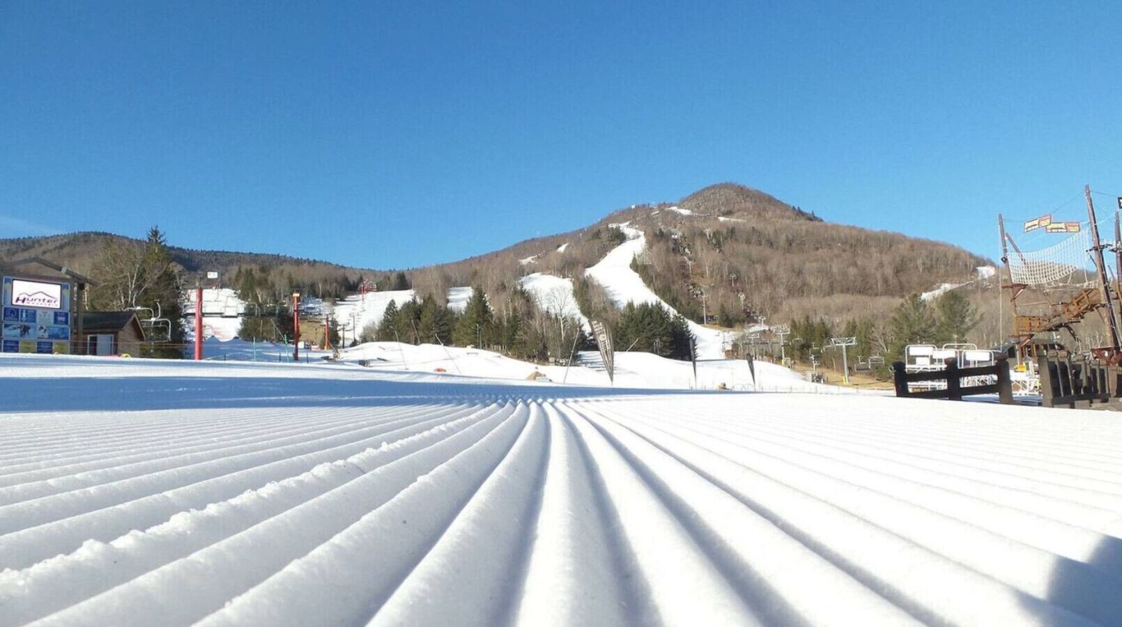 A snow-covered ski slope with a mountain in the background.