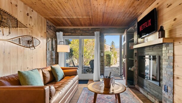 A cozy living room with a leather sofa, a fireplace, and a Netflix sign. - Cabin on Mtn, Seasonal Pool Access w Panoramic Views! Hike, Golf, Swim, Unwind! (Lanesville)