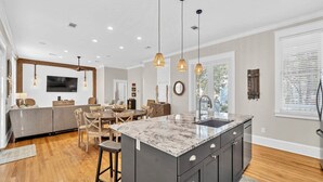 A modern kitchen with a marble island, dark cabinetry, and pendant lighting. - New List-4BR all en-suite steps to deeded beach and 2 community ‘1 heated’ pools (Santa Rosa Beach)