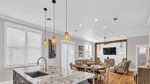 A modern kitchen with a marble island, wooden dining table, and pendant lights. - New List-4BR all en-suite steps to deeded beach and 2 community ‘1 heated’ pools (Santa Rosa Beach)
