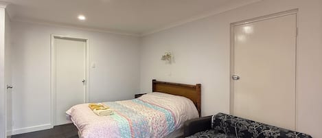 Un dormitorio con cama, sofá y dos puertas.