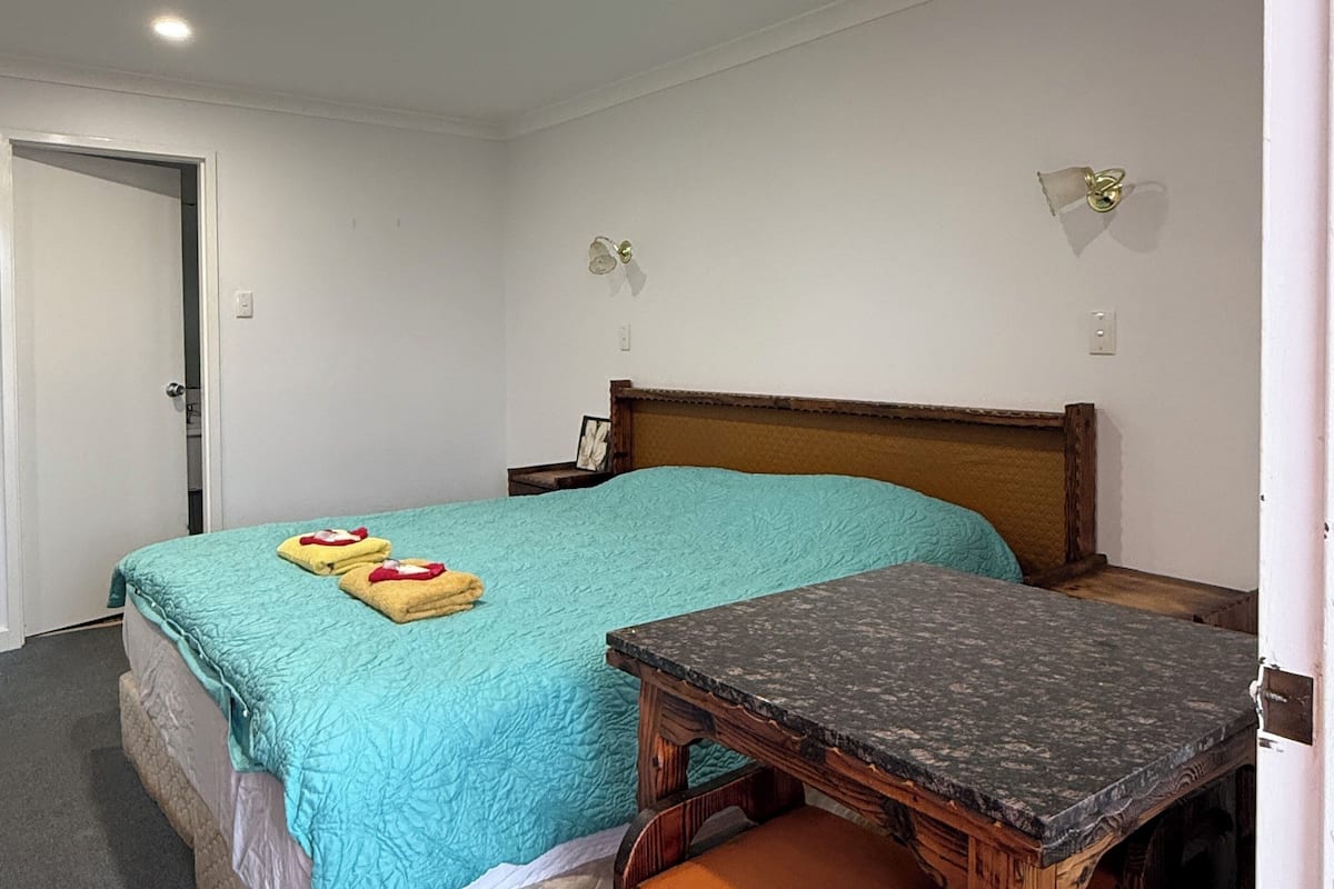 A bedroom with a bed, bedside table, and a door.