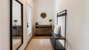 A hallway with a wooden bench, a round mirror, and a small plant on the bench.