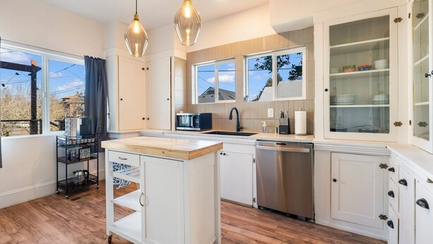 A modern kitchen with white cabinetry, a wooden island, and pendant lighting.