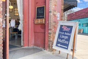 Une devanture de magasin avec un panneau en ardoise indiquant « 3610 SE Hartman » et une enseigne pour « The Waffle Window, gaufres de Liège fraîchement préparées ».