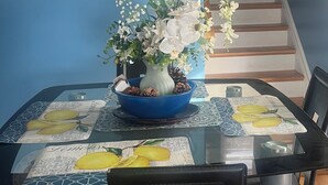 A dining table with a blue centerpiece, a clock on the wall, and a staircase in the background. - Charming 3-bedroom duplex with study space, WiFi in cool  Scituate. (Scituate)