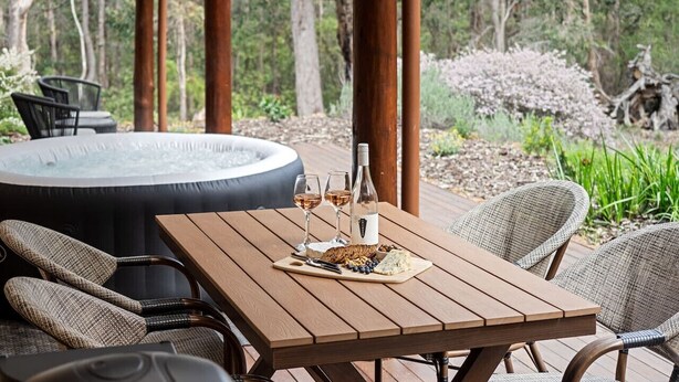 Una mesa de madera con un jacuzzi, sillas y una variedad de comida y bebidas.