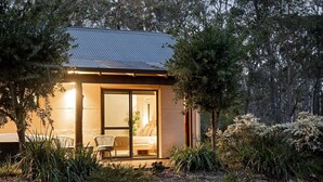 Una casa moderna con puerta de entrada de cristal, un área de comedor con sillas y un jardín con diversas plantas.