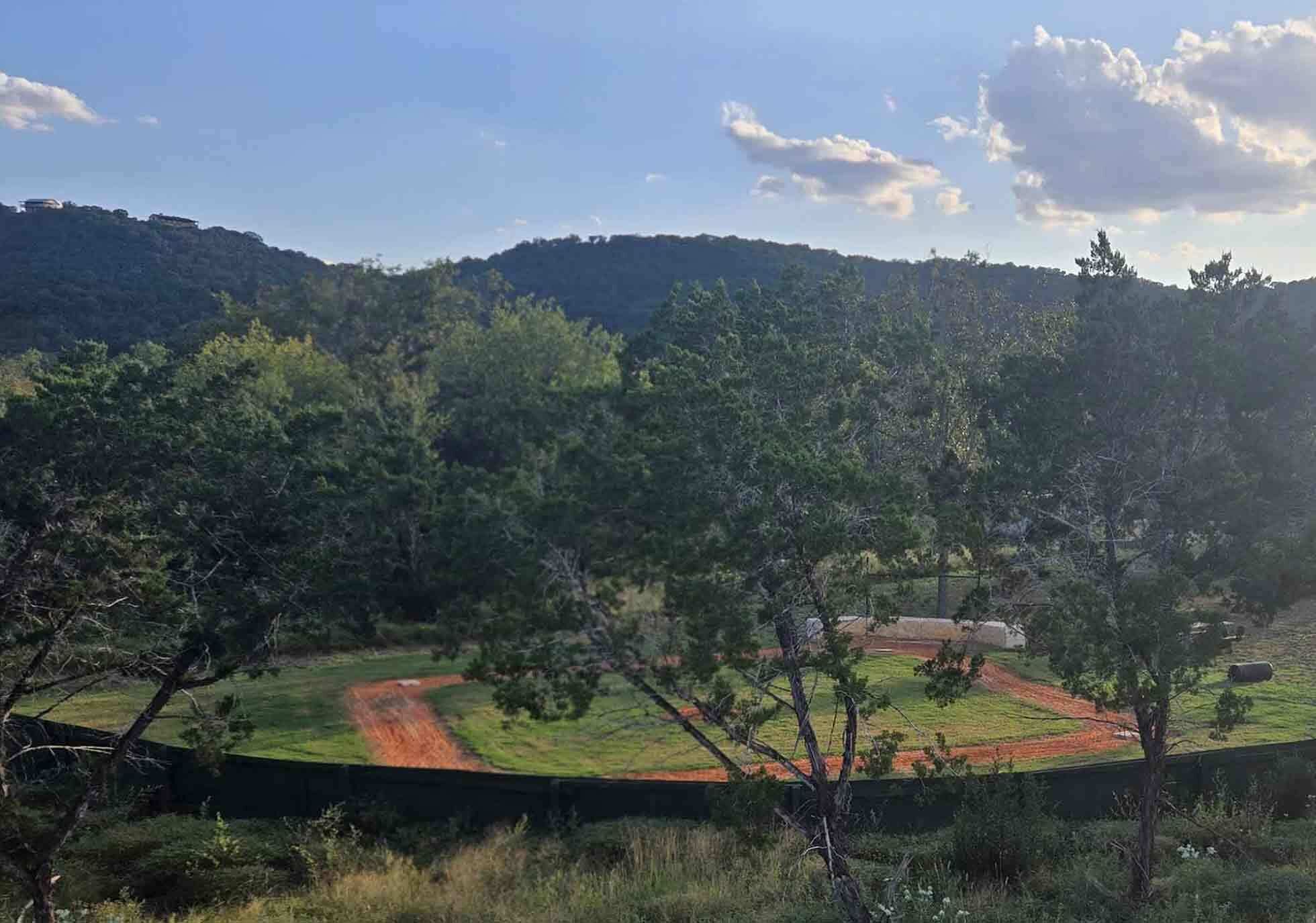 Um campo de beisebol rodeado por árvores e colinas.