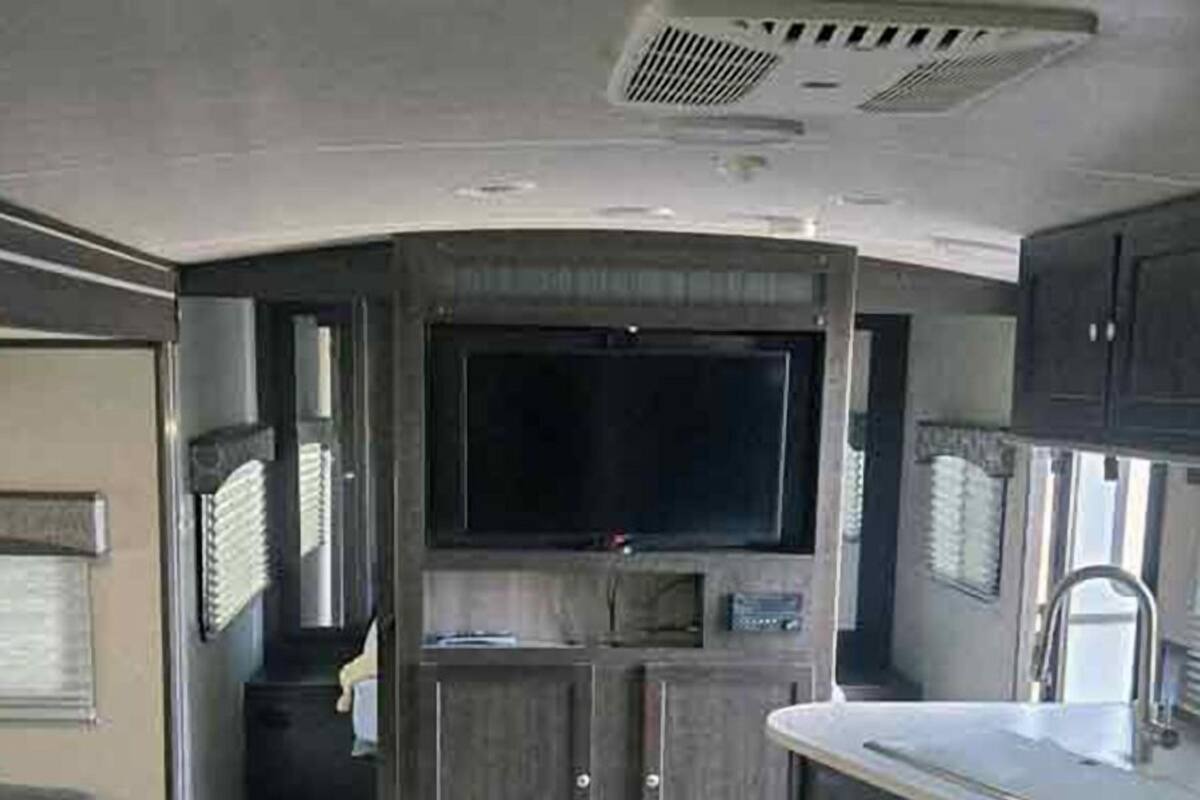 Cocina compacta para autocaravana con televisión integrada, un lavamanos y armarios.