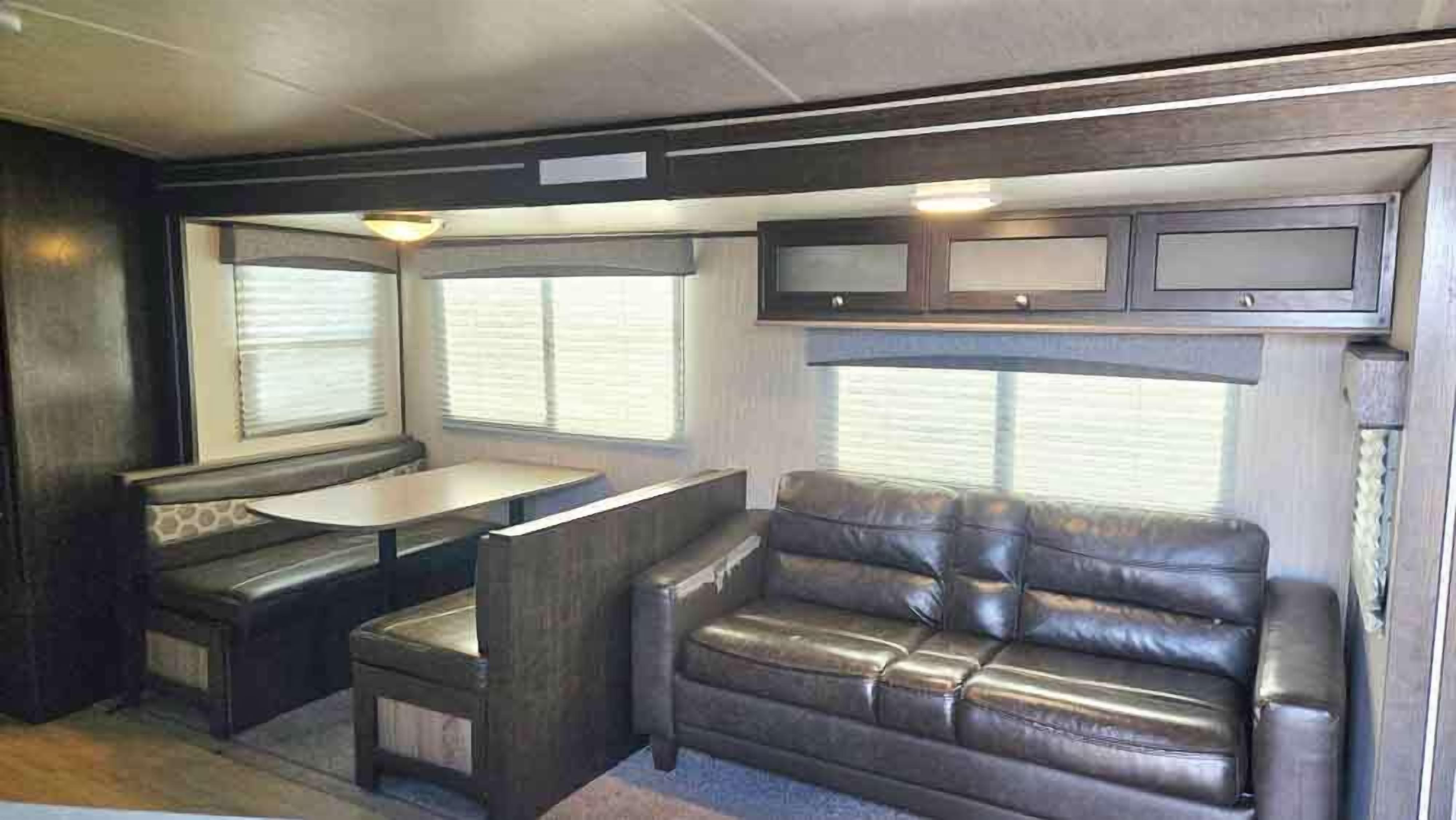 Ein kompaktes Wohnmobil-Interieur mit einer Küchenzeile, einem Essbereich und einer Sitzecke.