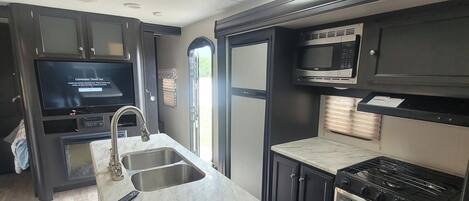 Una cocina moderna con estufa de acero inoxidable, microondas y pileta.