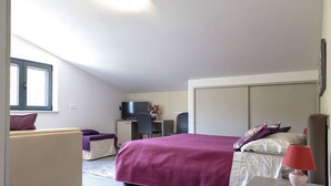 Une chambre à coucher comprenant un lit, un bureau, une chaise, un canapé et une lampe.