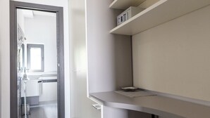 A modern kitchen with grey cabinetry, a countertop, and a built-in oven. There is a door leading to another room and a window above the sink.
