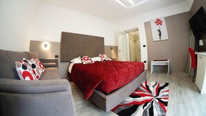 A modern bedroom with a bed, a sofa, a desk, and a shower area. - Alba Room - Room for 4 people with lake view (Campolattaro)