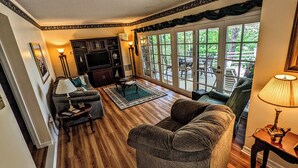 A living room with a wooden floor, a sofa, a coffee table, and a TV stand. - Grandview Getaway with a Million Dollar View! (Lakeville)