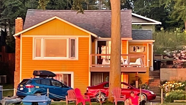 A two-story house with a dock extending into a body of water. - Enjoy beautiful sunsets at a Lake Side Cottage (Tipton)