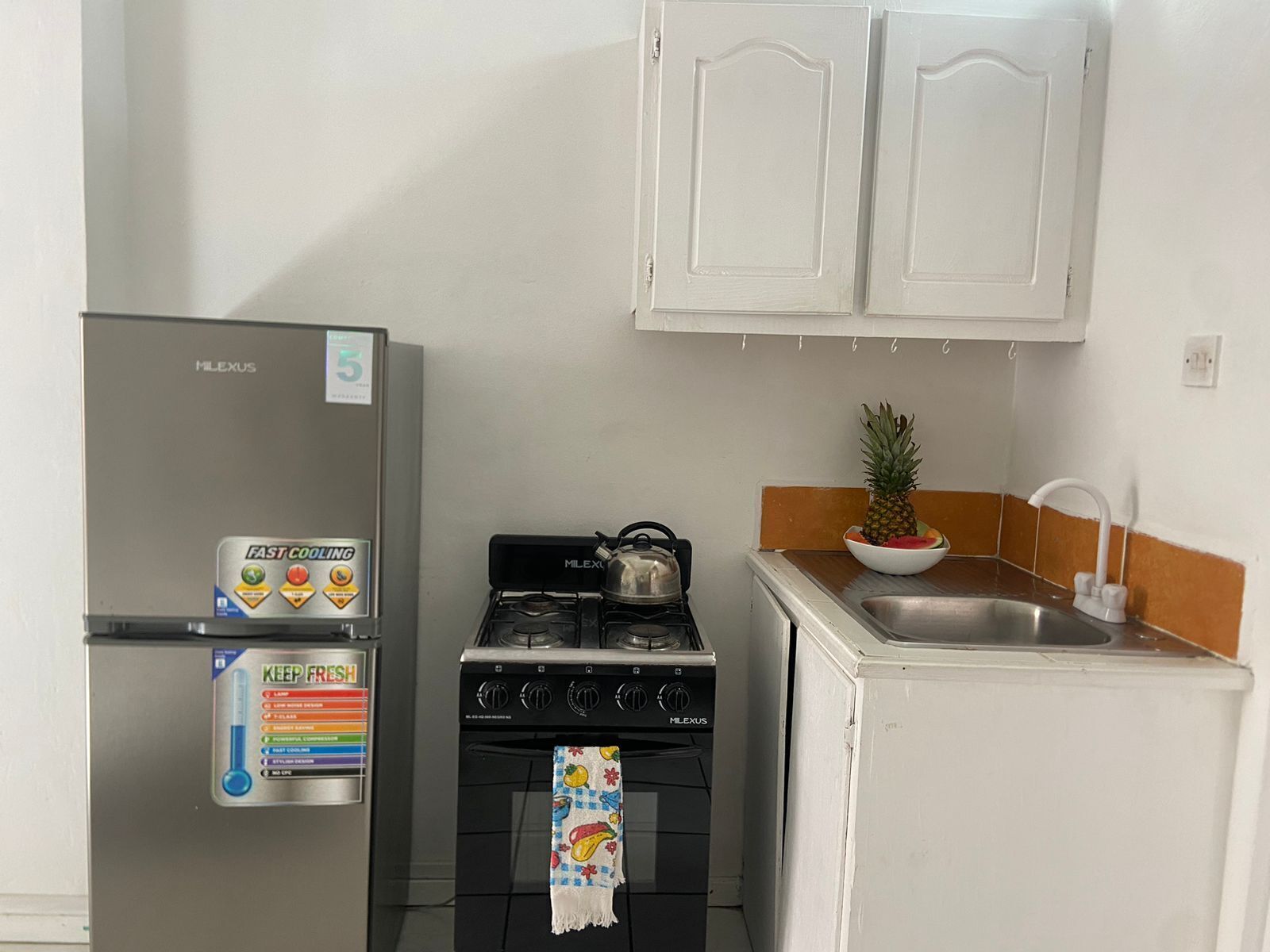 A compact kitchen with a refrigerator, stove, and sink.