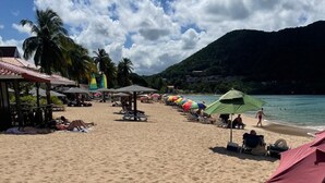 Una playa con sombrillas, sillas de descanso y cielo despejado.
