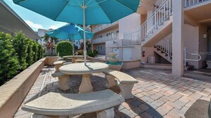 A courtyard with outdoor seating, a fountain, and a staircase leading to an upper level. - Your Beachside Retreat – Siesta Key’s White Sands Just Steps Away! (Siesta Key)