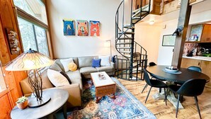 Un salon chaleureux avec un canapé, une table basse et un escalier en colimaçon.