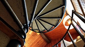 Un escalier en colimaçon avec une structure intérieure en bois et une vue sur l’étage supérieur.