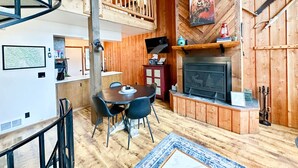 Un intérieur de chalet chaleureux avec un coin repas, une cheminée et des murs en bois.