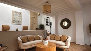 Un accogliente soggiorno con una zona divani, un tavolino rotondo in legno e una lampada decorativa.