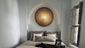 Una camera da letto con un letto grande, un pannello decorativo a parete e una finestra con persiane bianche.