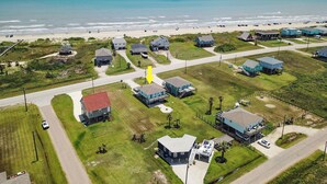 Vue aérienne d’une zone résidentielle côtière, avec des maisons, une plage et une route.