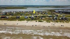 Vue aérienne d’une communauté côtière, avec des maisons, une plage et des étendues d’eau adjacentes.