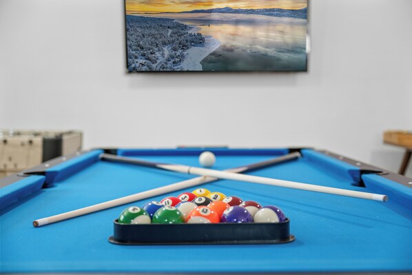 A pool table with a blue felt surface, a white cue stick, and colorful balls.