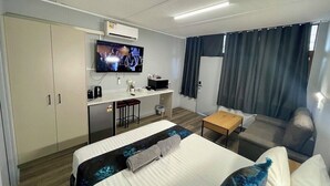 Ein Hotelzimmer mit Bett, Schreibtisch, Fernseher und einer Couch.