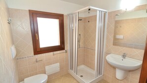 A bathroom with a toilet, a shower enclosure, and a sink.