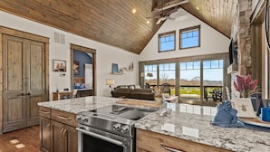 A spacious kitchen with a large island, wooden cabinets, and a stone fireplace. - Sommer Hus at Eagles Nest: Pet Friendly Single Level (Banner Elk)