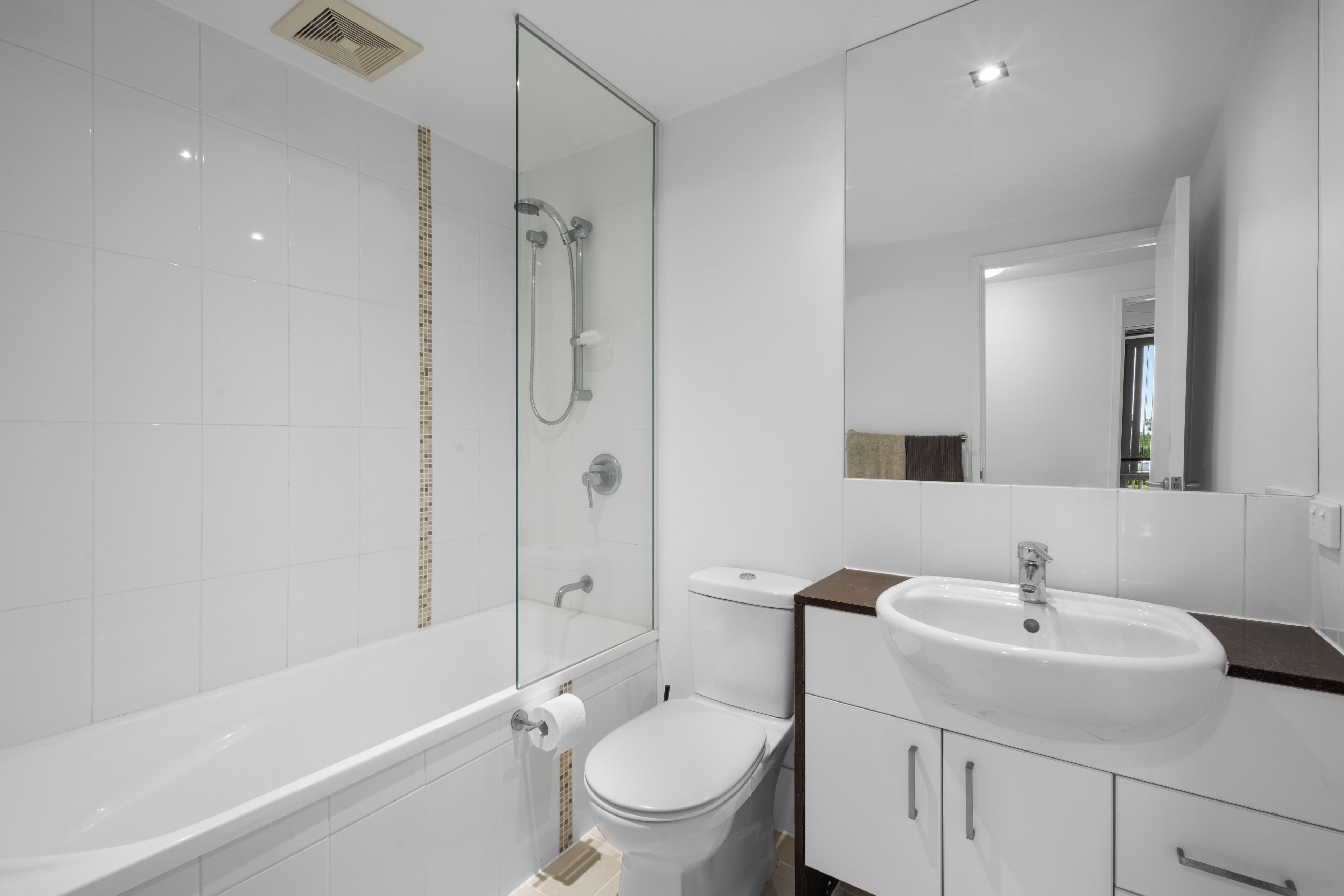 A modern bathroom with a glass-enclosed shower, a white toilet, and a sink with a marble countertop.