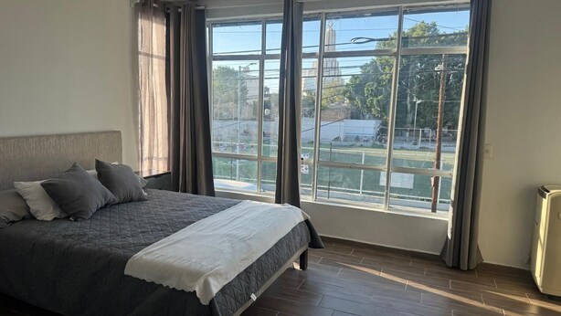 A bedroom with a large bed, a view of the outside, and a radiator. - Hermosa Province Duplex House (Large Groups) (Guadalajara)