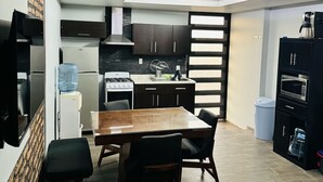 A compact kitchen with a dining area, a water dispenser, a stove, and a microwave. - Hermosa Province Duplex House (Large Groups) (Guadalajara)