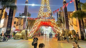 A tall, illuminated tower with a flame on top, surrounded by banners and a large golden lion statue. - Hermosa Province Duplex House (Large Groups) (Guadalajara)