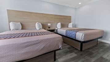 Una camera d'albergo con due letti, una testiera in legno e un comodino.