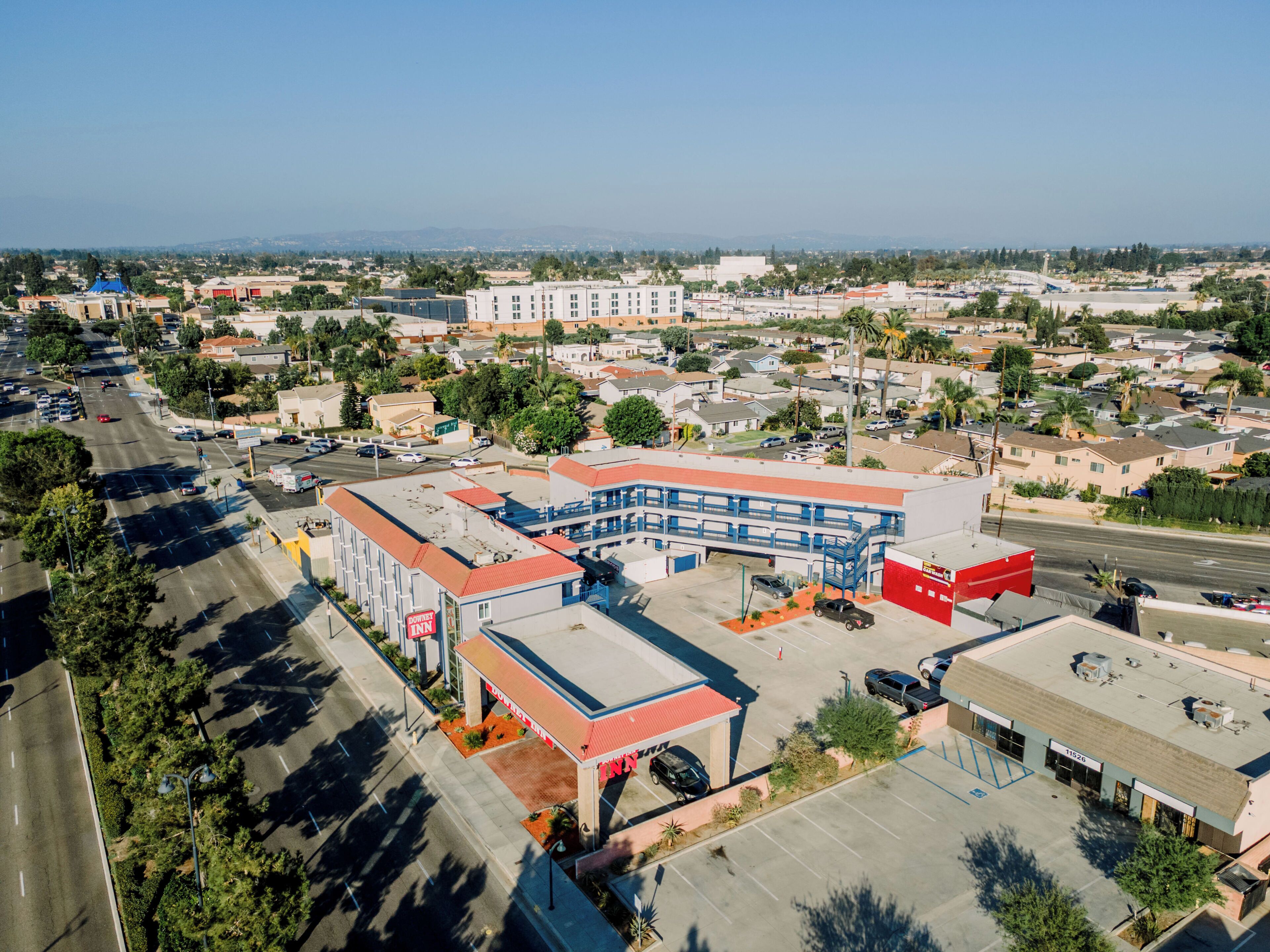 A downtown area with a prominent DOWNTOWN INN hotel featuring a red and blue building, a parking lot, and surrounding residential and commercial buildings.