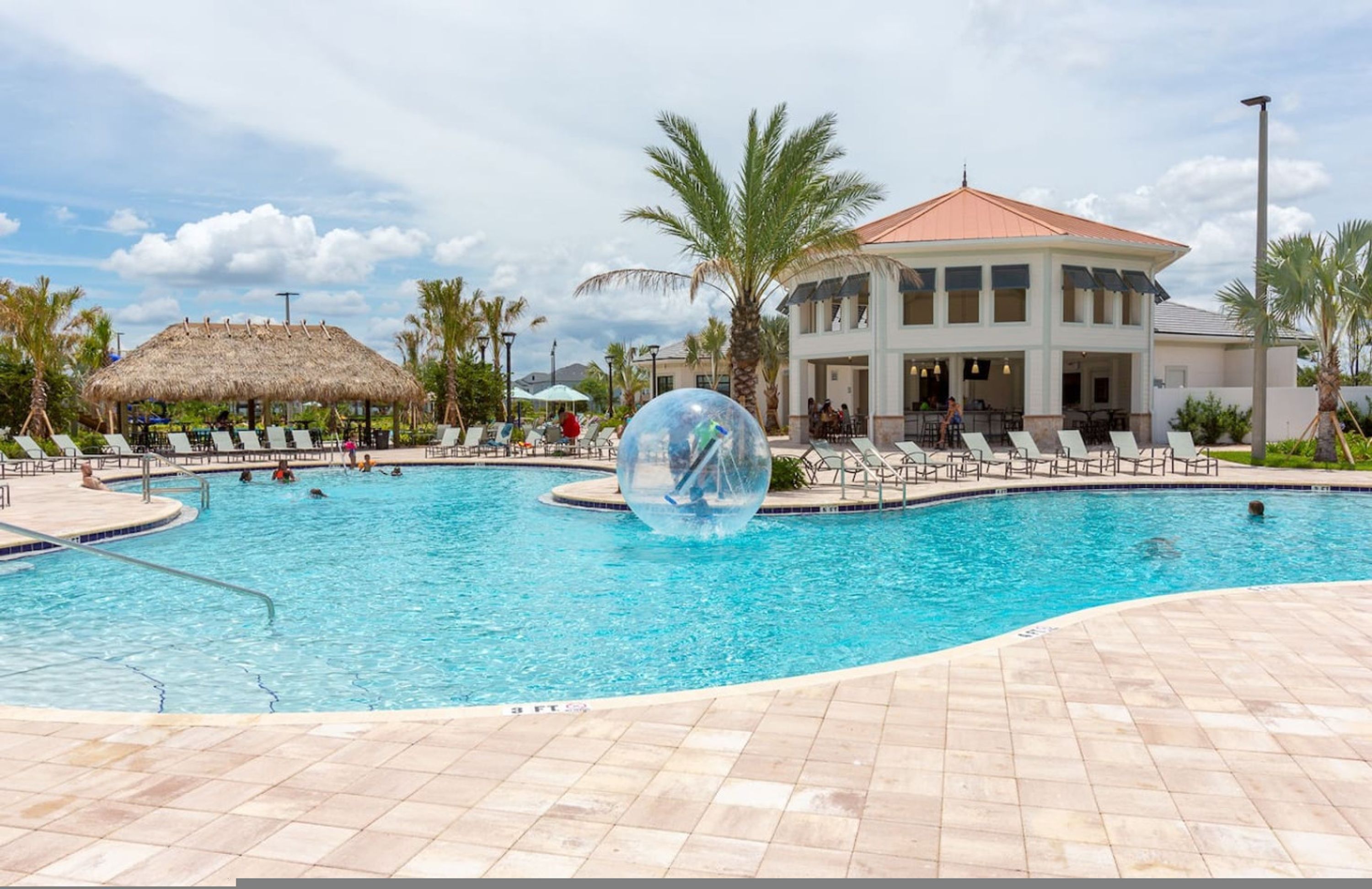 A swimming pool with lounge chairs and a thatched-roof structure.