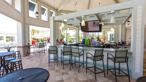 An outdoor bar area with high ceilings, a TV mounted above the bar, and several chairs and tables. - Your 5bdr House w Pool - 4959 (Kissimmee)