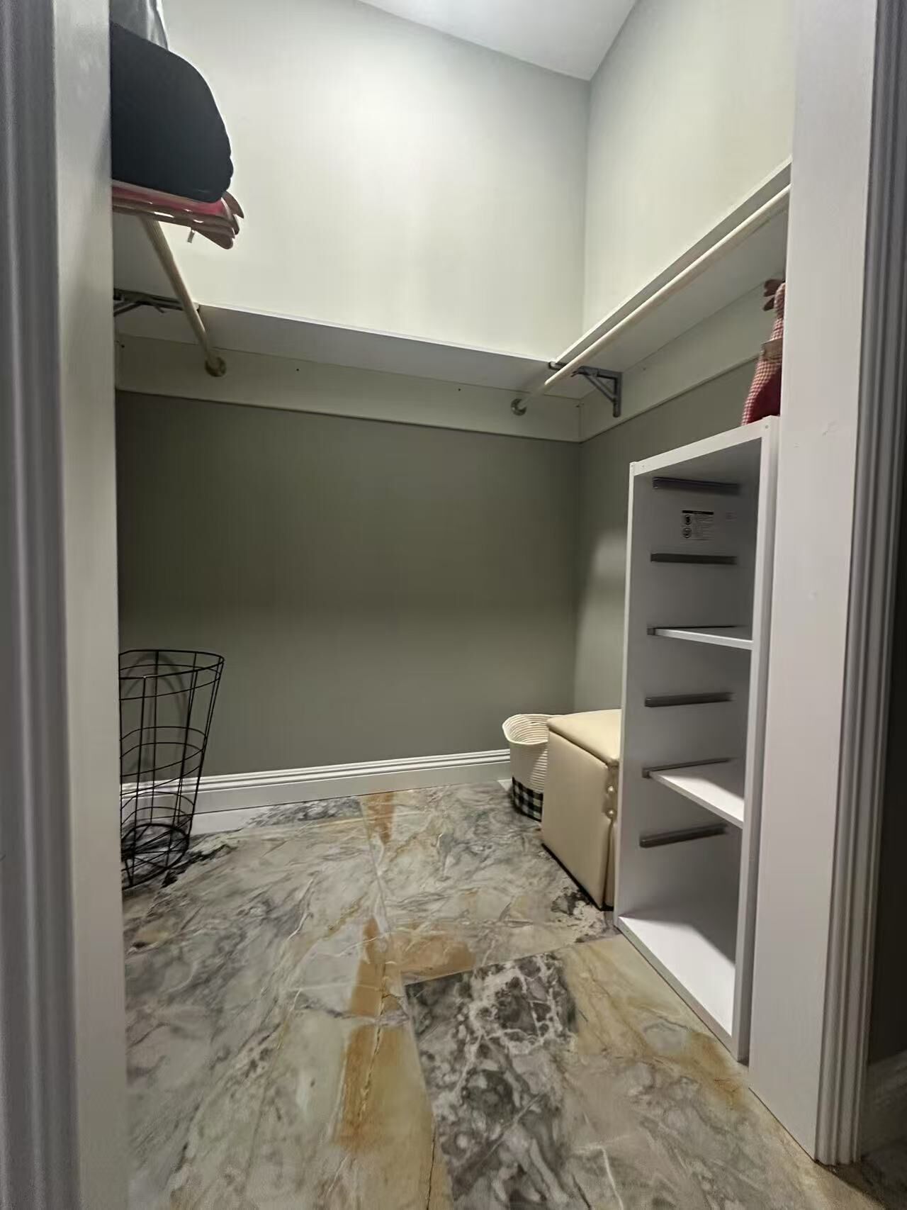 A walk-in closet with a marble floor, a white shelving unit, and a metal rack.
